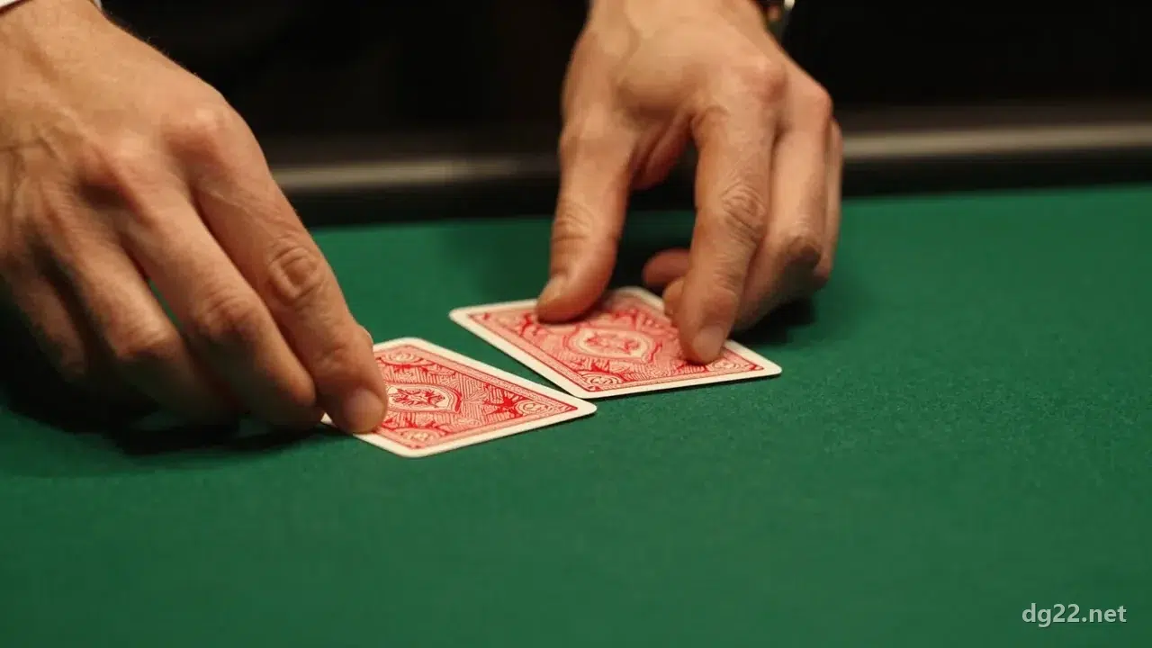 DG 真人有哪些遊戲?七款桌台一次看——同一個廳館,成本從 1.06% 到 30% 差 28 倍 2 荷官雙手把兩張背面朝上的紅色撲克牌並排推到素面深綠絨布上的特寫